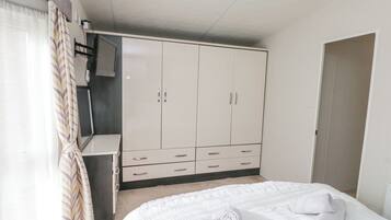 A bedroom with a bed, a wardrobe, and a television.