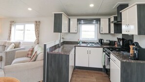 Una cocina compacta con armarios blancos y gris oscuro, una isla central y un ventanal que proporciona luz natural.
