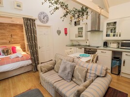 Um quarto acolhedor com cama, sofá listrado, mesa de jantar e área de cozinha.