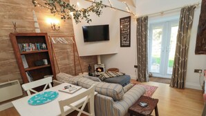 Una sala de estar acogedora con un sofá modular, una mesa de comedor y un televisor instalado en la pared.