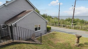 A small, single-story building with a white exterior and a black metal staircase leading to a small porch. - Morva (New Quay)