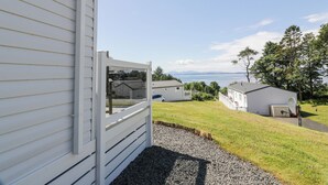 A white mobile home with a large window, a gravel driveway, and a view of a lake and mountains. - Bethany's Retreat (Wemyss Bay)