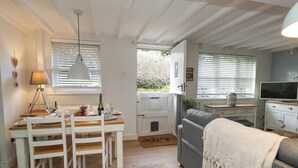 A cozy living room with a grey sofa, a white coffee table, and a TV on a wooden stand. - The Cottage (Swanage)