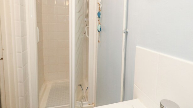 A bathroom with a shower area, a toilet, and a sink. - The Cottage (Swanage)