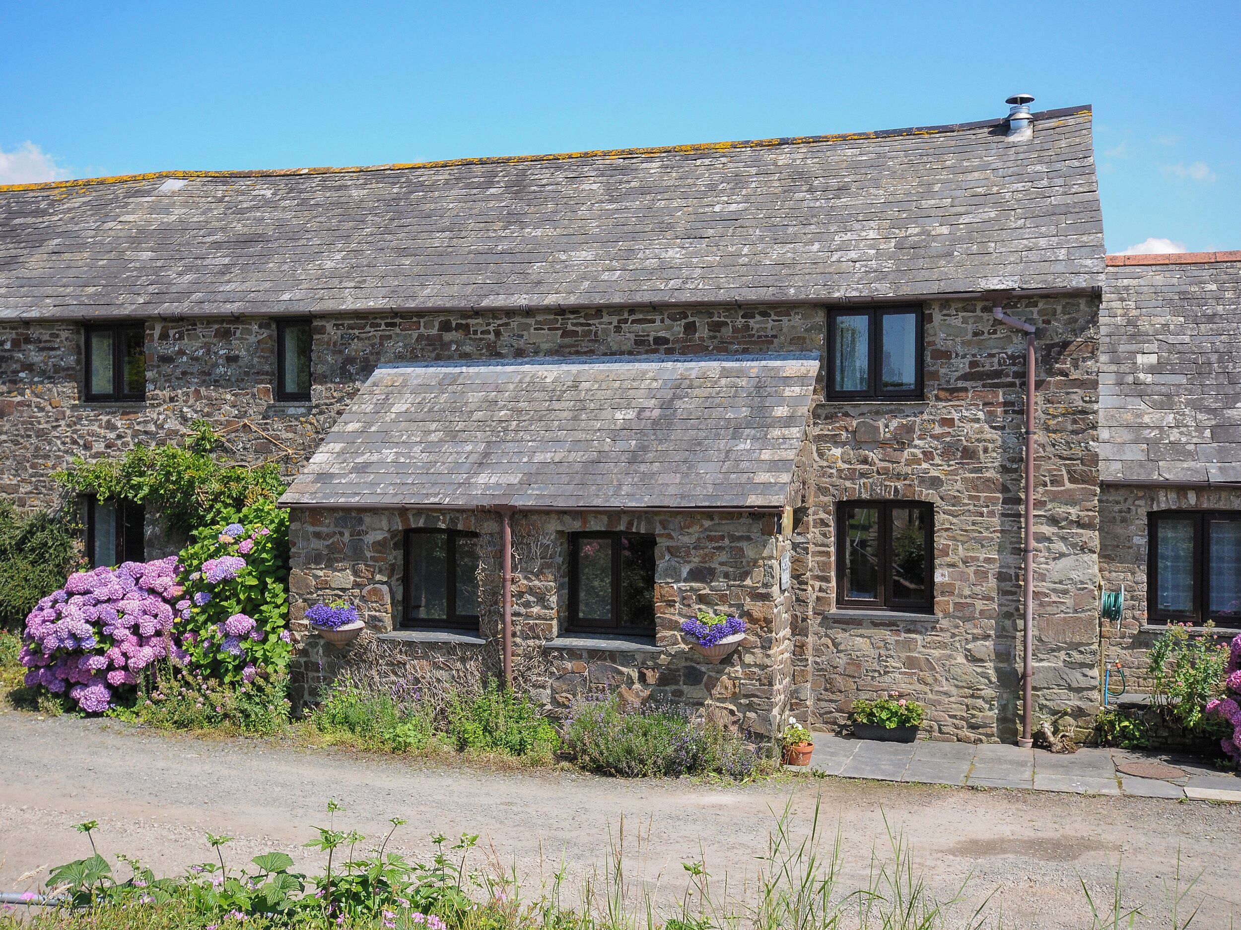 A stone building with a sloped roof, multiple windows, and a small porch area.