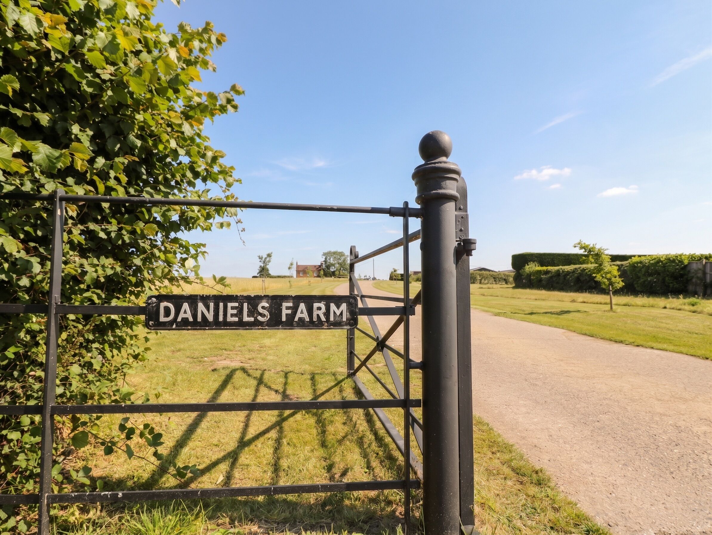 A metal gate with a sign reading 'DANIELS FARM' and a clear sky.