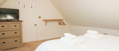 A bedroom with a bed, a dresser, a television, and a hanging rack.