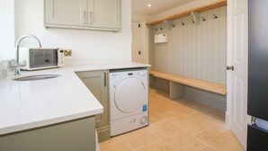 A compact kitchen with a microwave, sink, and washing machine. - Daniels Farmhouse (Worcester)