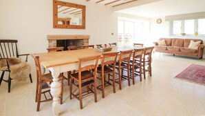 A spacious dining area with a wooden table and chairs, a fireplace, and a large mirror on the wall. - Daniels Farmhouse (Worcester)