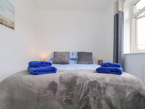 Ein ordentlich bezogenes Bett mit blauen Handtüchern, einer blauen und weißen Bettdecke und zwei Kissen.