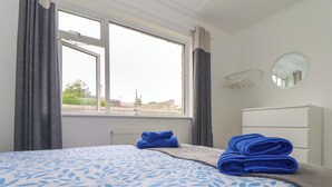 Une chambre d’hôtel avec un lit, une fenêtre avec des rideaux, un radiateur et un miroir au mur.