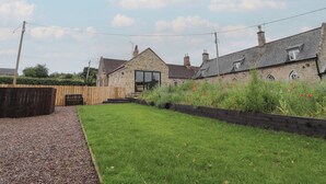 A stone house with a large window and a wooden fence. - Honeysuckle Cottage (Cornhill on Tweed)