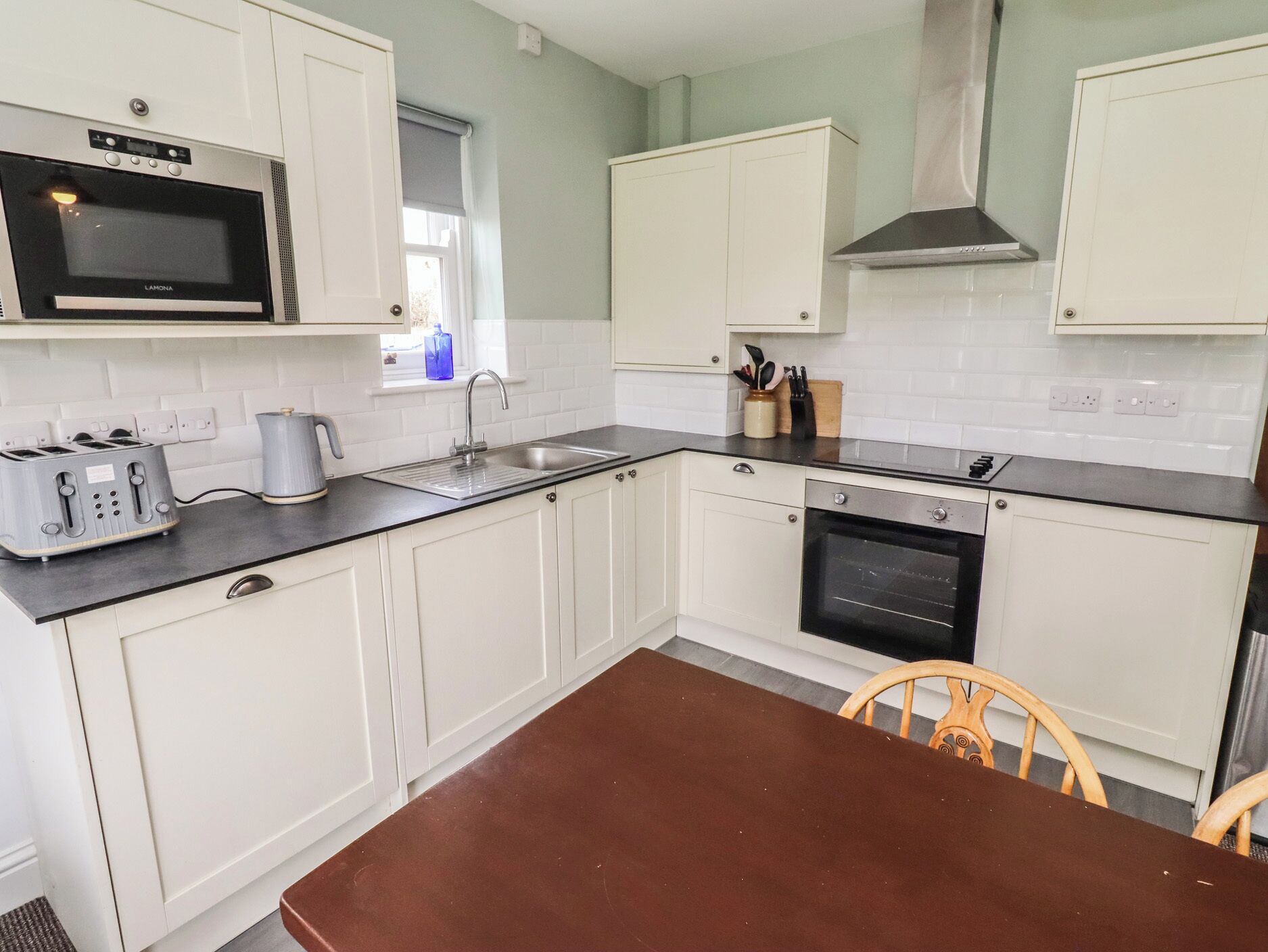 A kitchen with white cabinets, a microwave, a toaster, a sink, and a stove.
