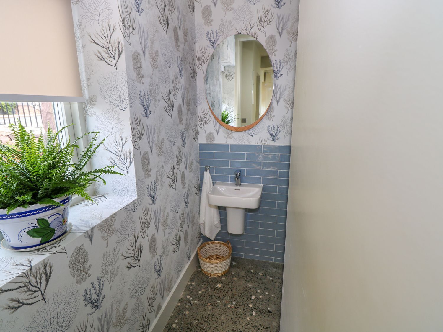 A bathroom with a sink, a mirror, a potted plant, and a window.