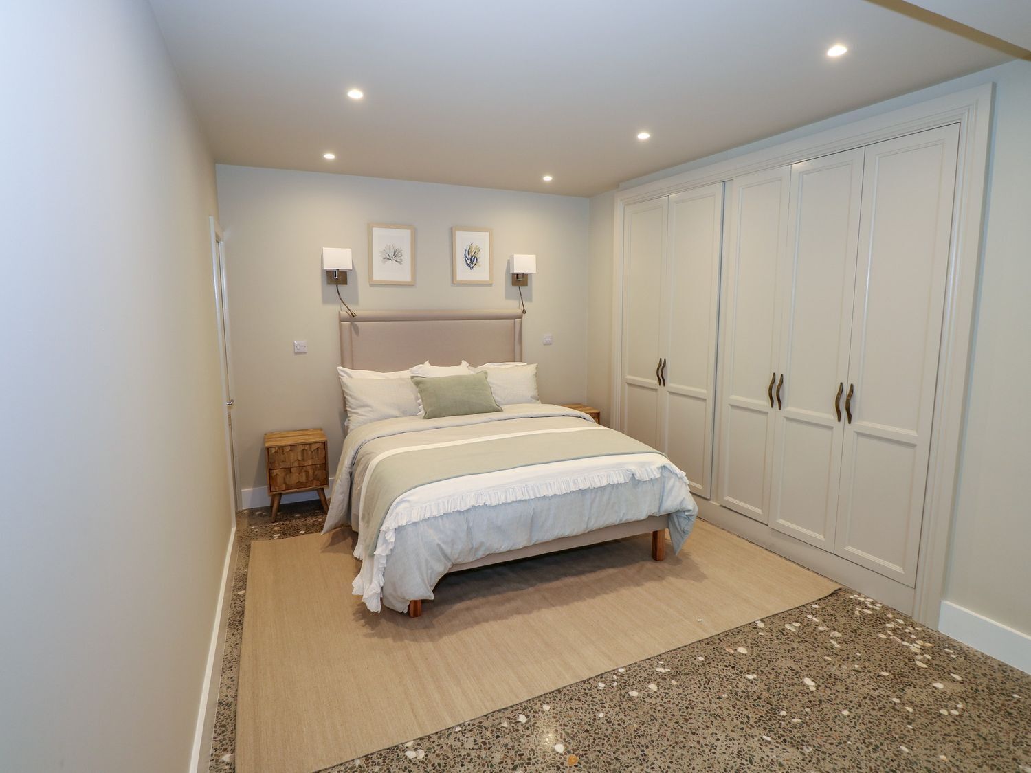 A bedroom with a bed, bedside tables, a wardrobe, and wall-mounted lights.