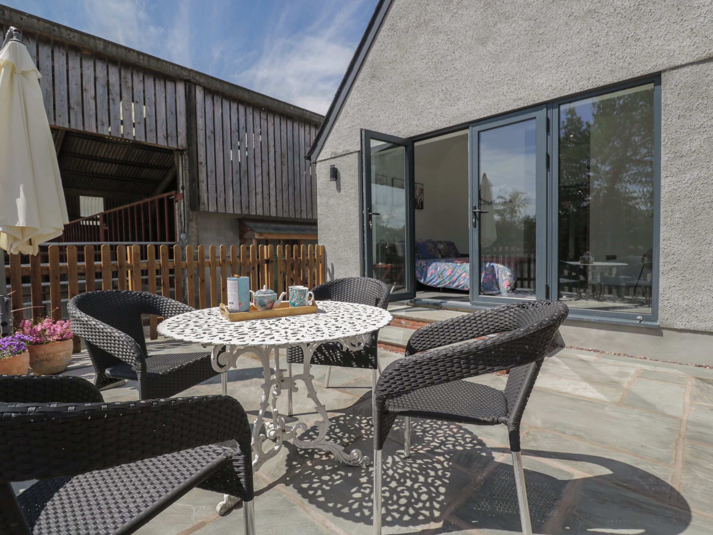 An outdoor patio with wicker chairs, a round table, and a white umbrella.