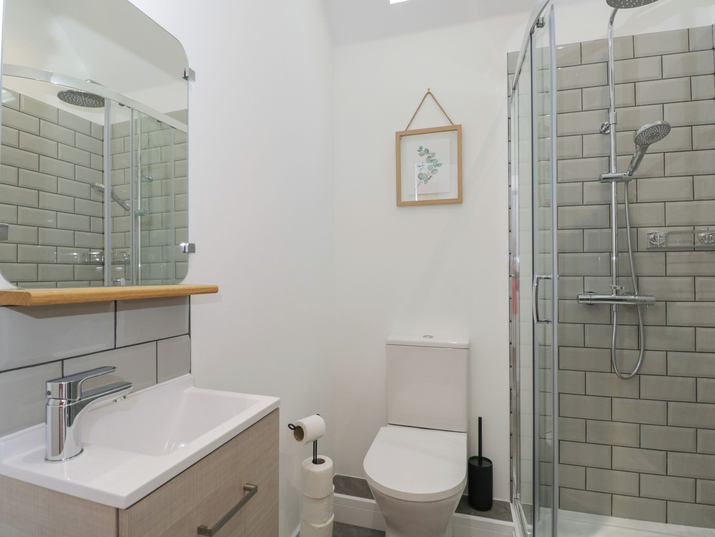 A modern bathroom with a glass-enclosed shower, a white sink, and a toilet.
