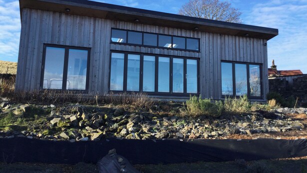 A modern building with large windows and a wooden exterior. - Tirlaggan House (Oban)