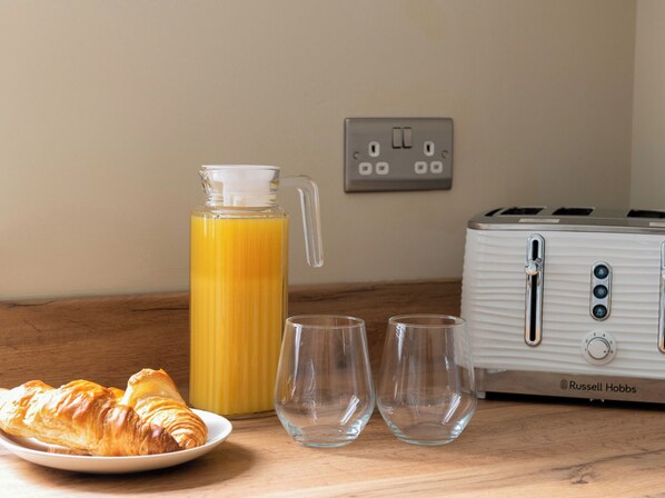 A breakfast setting with croissants, a glass of water, and a glass of orange juice on a wooden table.