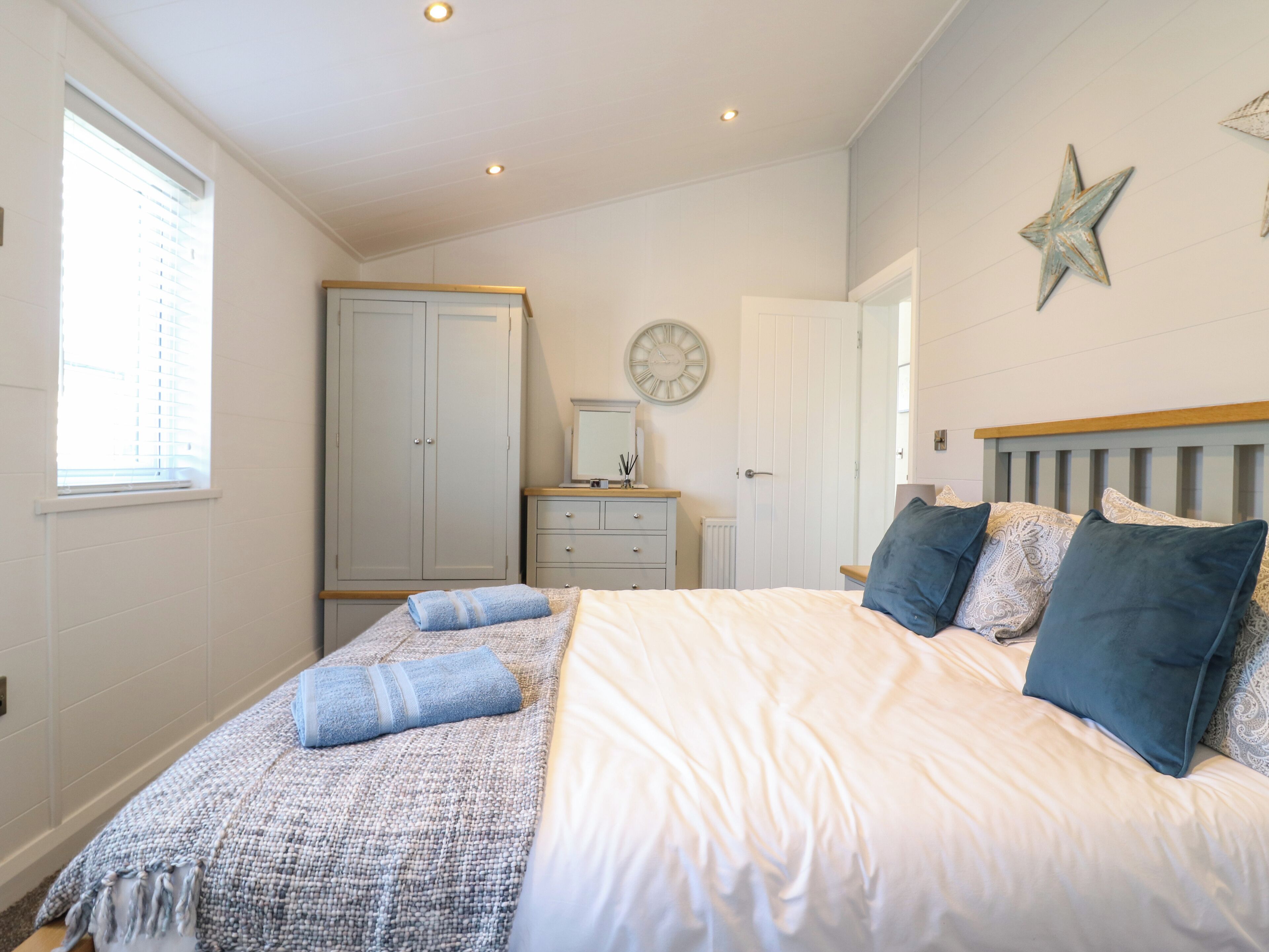 Ein Schlafzimmer mit Bett, Kommode, Kleiderschrank, Fenster und einer Sterne-Dekoration an der Wand.