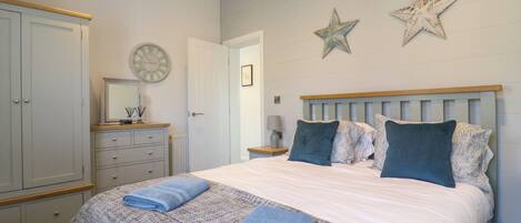 A bedroom with a large bed, a wardrobe, a nightstand, and a wall clock.