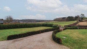 A rural landscape with a gravel path leading through a green field, bordered by hedges and trees. - Nettleford Inhale (Tarporley)