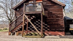 A rustic wooden cabin with a wooden staircase leading to a balcony.