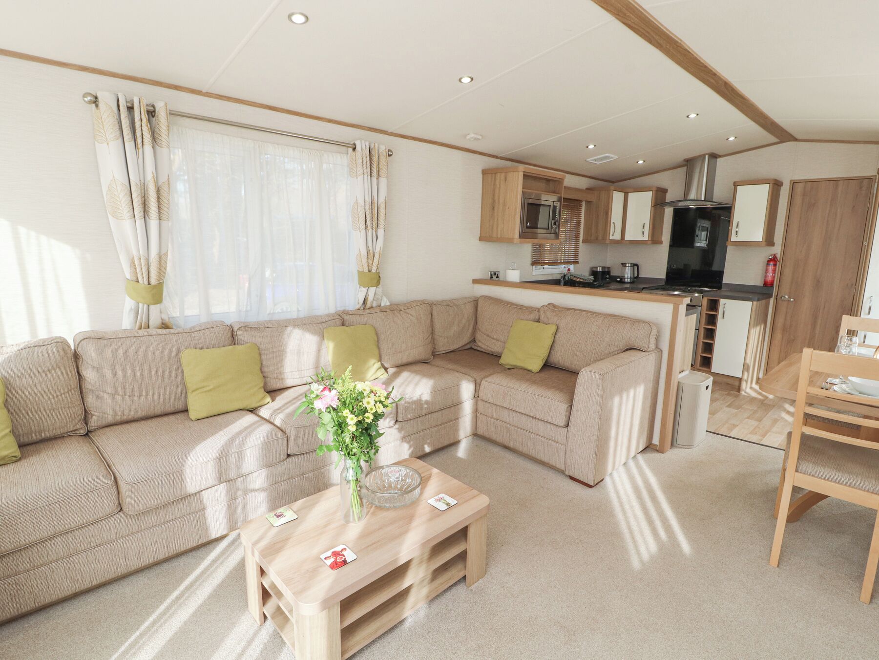 A compact living space with a sofa, a coffee table, and a kitchen area including a microwave and stove.
