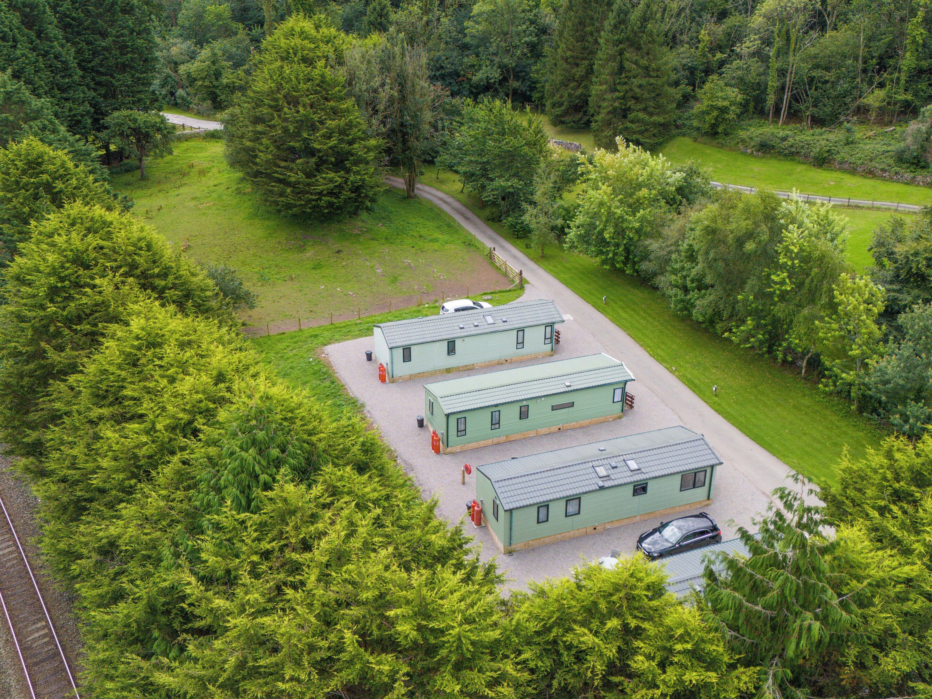 A green-roofed building complex with a gravel driveway and a parked car.
