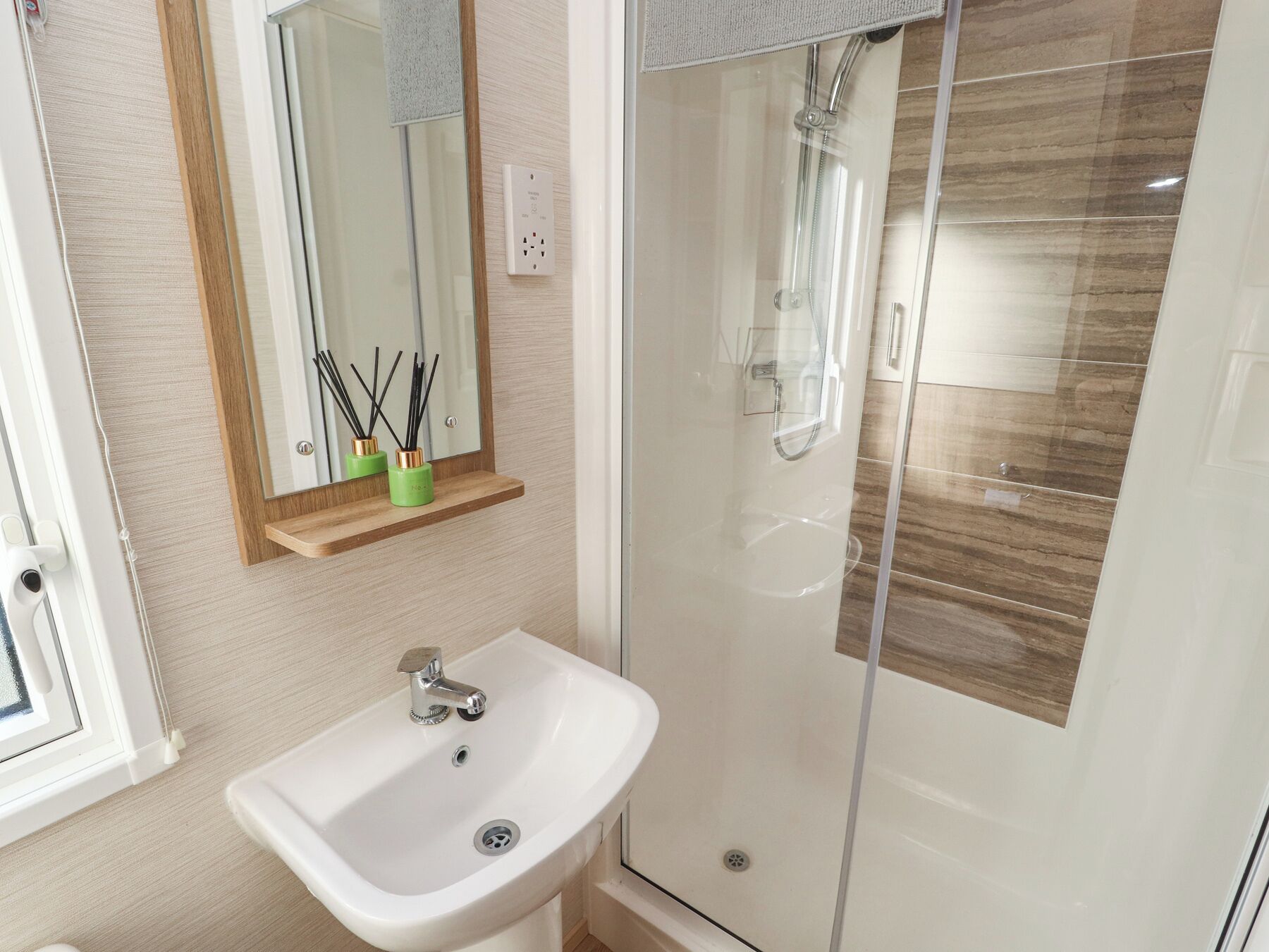 A bathroom with a sink, mirror, and shower.