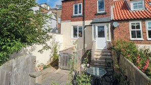 A two-story house with a brick facade, a small front garden, and a wooden gate. - 6 Clarence Place (Whitby)