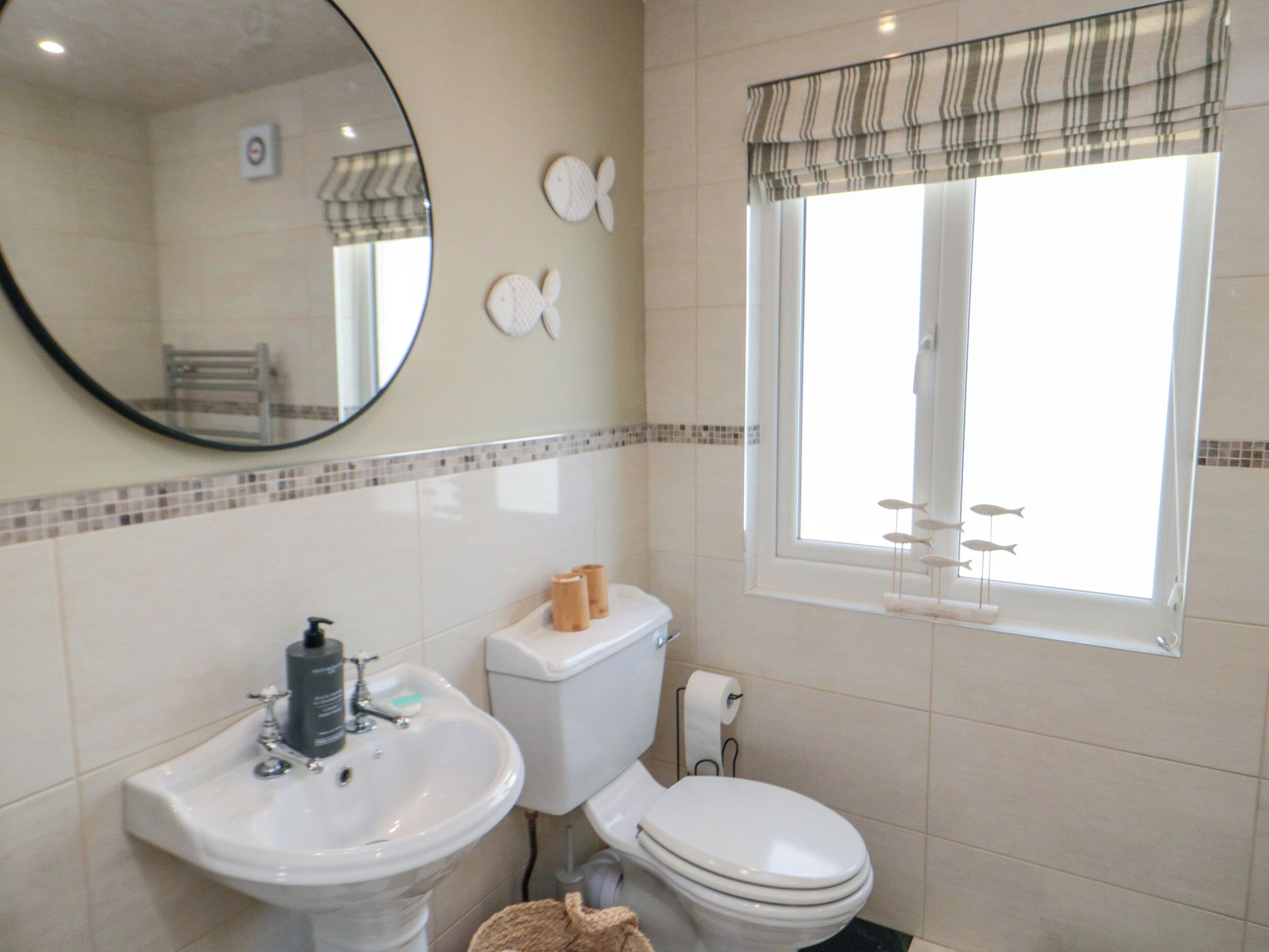 A bathroom with a sink, toilet, and a window with a view of the outside.