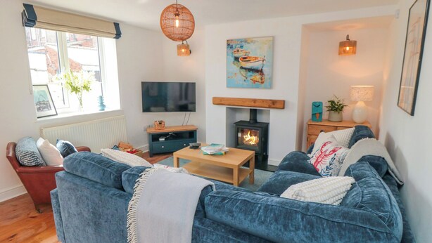 A living room with a sofa, a wooden coffee table, a television, a fireplace, and a window with a view of the outside. - 6 Clarence Place (Whitby)