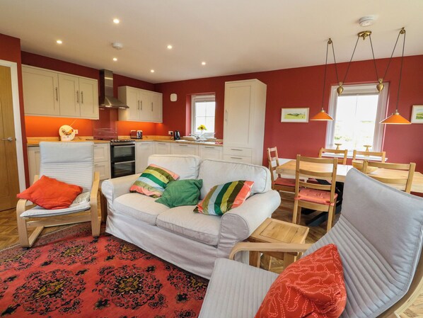 A cozy living room with a sofa, chairs, a dining table, and a kitchen area. - Tirlaggan Úr (Oban)