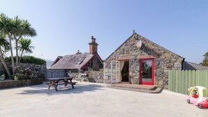 Un bâtiment en pierre avec une porte rouge et une table de pique-nique devant.