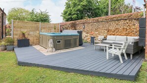 Ein Garten mit Whirlpool, Gartenmöbeln und einer Steinmauer.