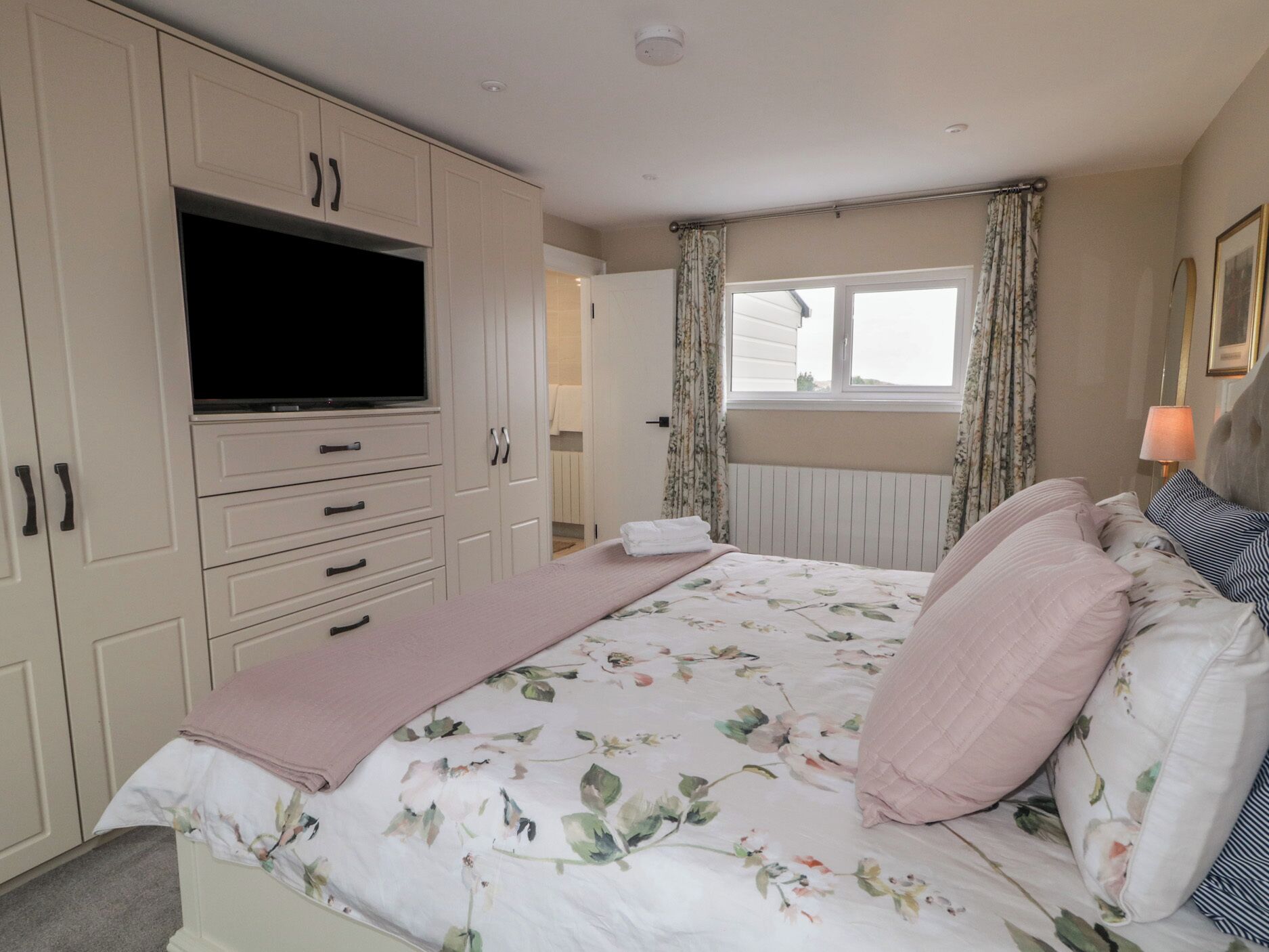 Un dormitorio con cama, televisor y ventana con cortinas.