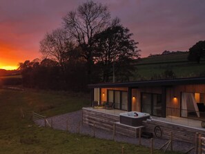 A modern house with a hot tub on the porch, surrounded by a fence and a grassy field. - The Lookout (Preston)