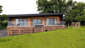 A modern house with a wooden exterior, large windows, and a balcony with outdoor seating. - The Lookout (Preston)