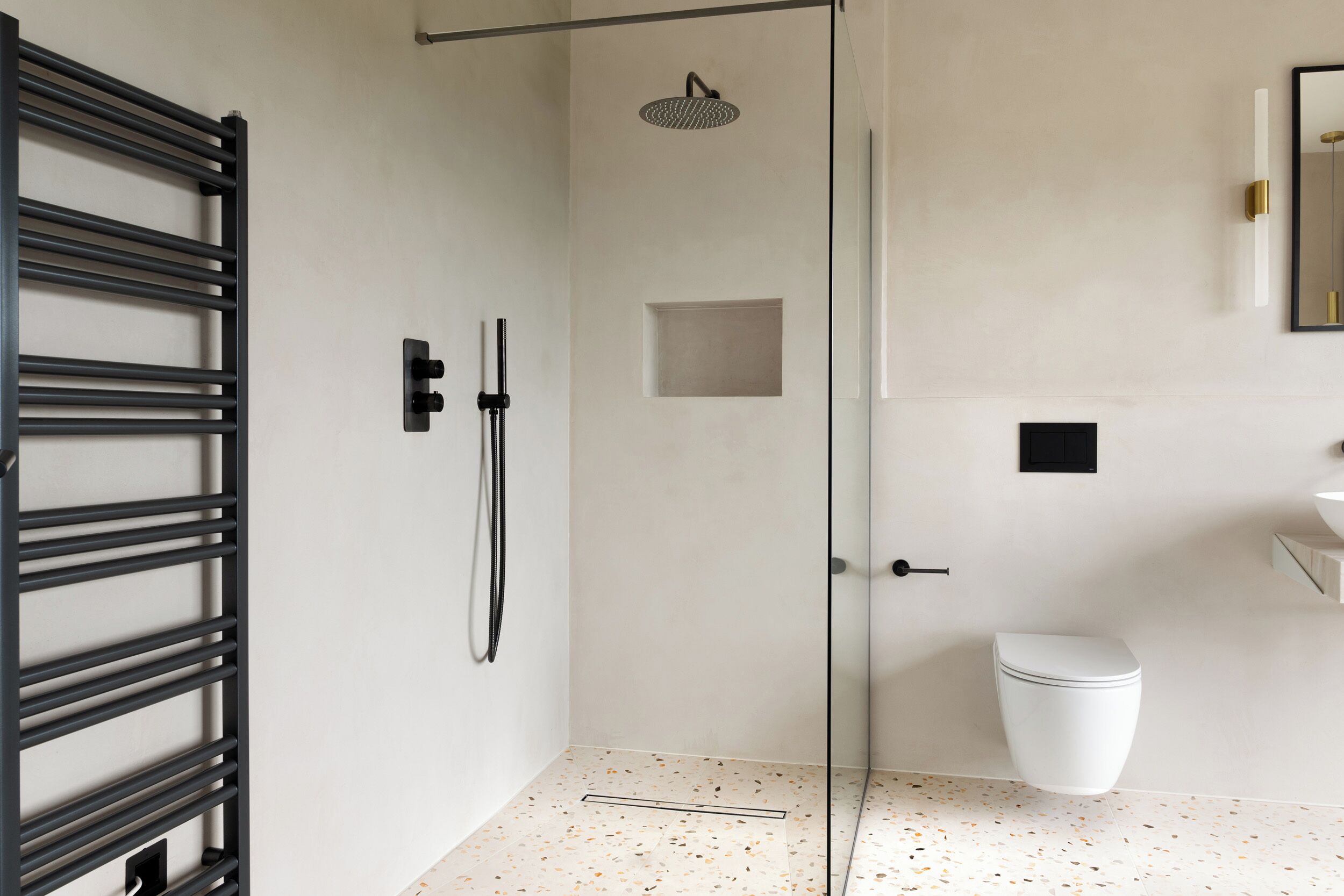 A modern bathroom with a glass shower enclosure, a white toilet, and a minimalist sink area.