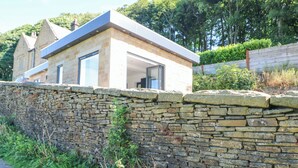 A stone wall with a modern house behind it. - Priestleys Retreat (Blackburn)