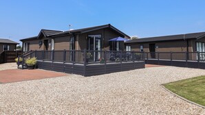 Un bâtiment moderne doté d’une allée en gravier, d’un patio couvert et d’un espace extérieur clôturé.