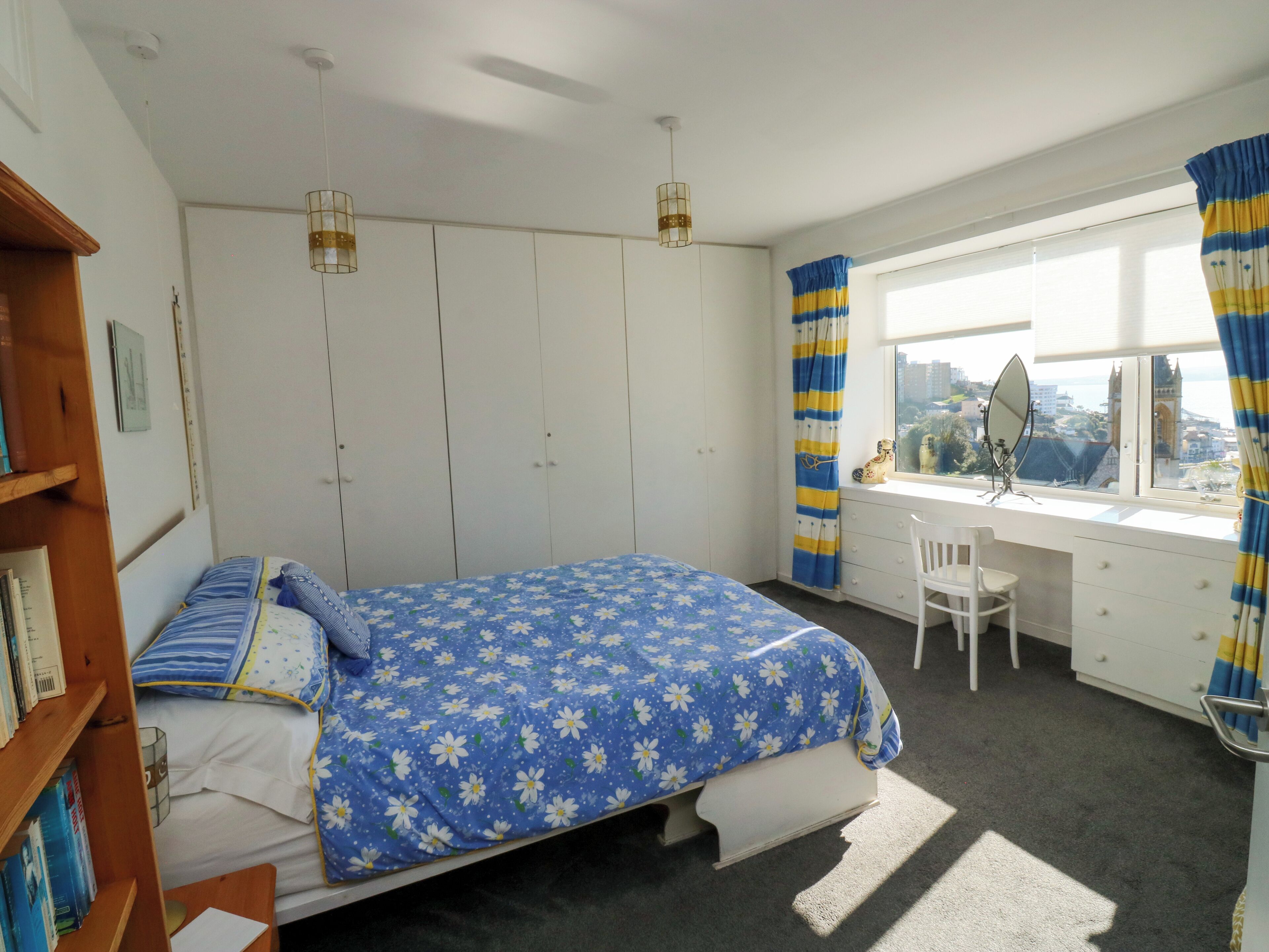 Une chambre à coucher comprenant un lit, un bureau, une chaise, une armoire et une fenêtre avec des rideaux.