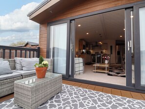 A modern patio with wicker furniture, a glass table, and a potted plant. - Kingfisher Lodge 36 (Evesham)
