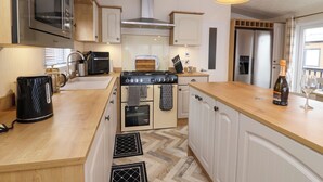 Eine moderne Küche mit Backofen, Gasherd, Kaffeemaschine und einer Weinflasche.