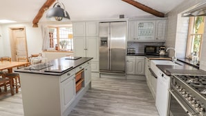 Een moderne keuken met een centraal eiland, roestvrijstalen apparatuur en een plafond in boerderijstijl.