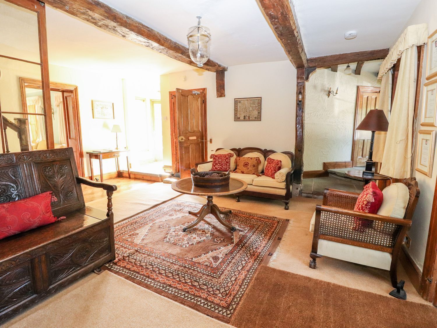 A traditional living room with a wooden sofa, a round coffee table, and a patterned rug.