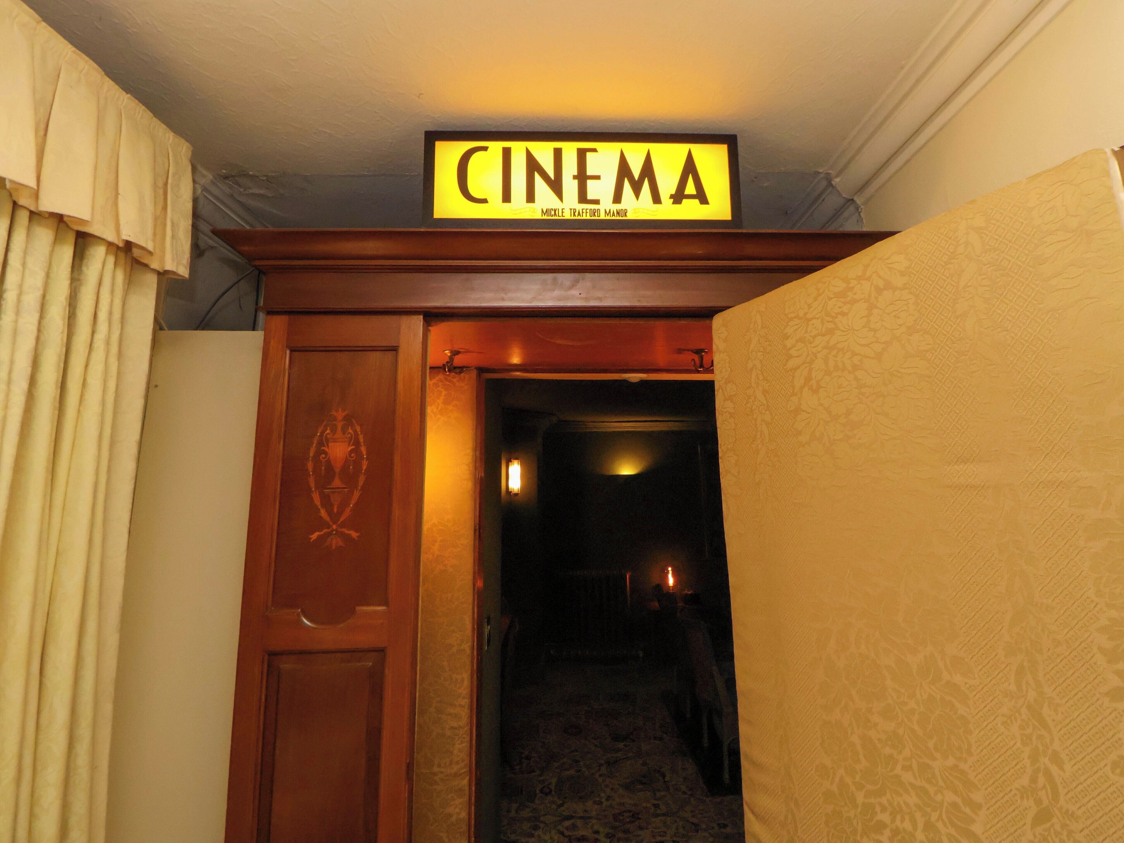 A cinema sign above a doorway leading to a dimly lit hallway.