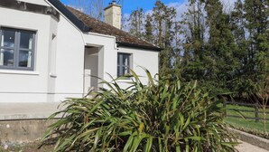 A white building with a tiled roof, a chimney, and a small porch.