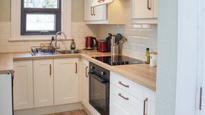 A kitchen with white cabinets, a wooden countertop, a built-in oven, and a window above the sink.